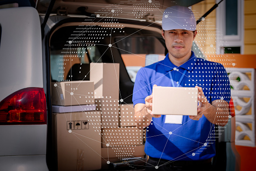 Delivery man holding package in front of cargo van delivering package,Technologies connecting the world.