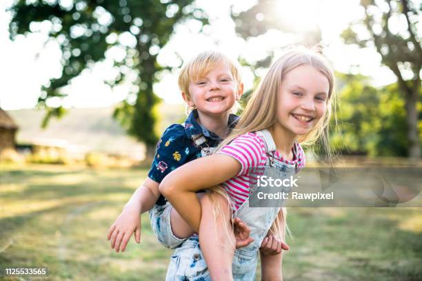 Girl Giving Her Brother A Piggyback Ride Stock Photo - Download Image Now - Child, Playing, Playful