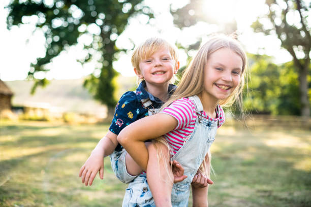 dziewczyna dająca bratu przejażdżkę piggyback - outdoors playing family spring zdjęcia i obrazy z banku zdjęć