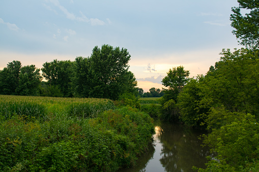 Summer sunset with reflections off the small creek.  Bureau County, Illinois, USA