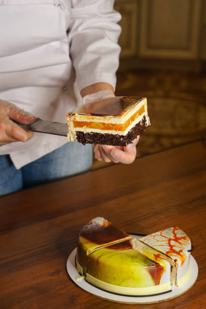 istock Confectioner cuts dacquoise cake in mirrored glaze. 1125537453
