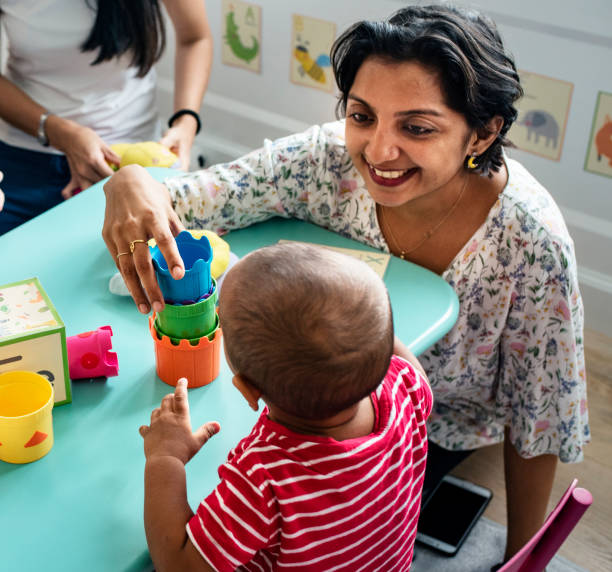 kind-bausteine mit einem lehrer in der baumschule - child playroom parent indoors stock-fotos und bilder