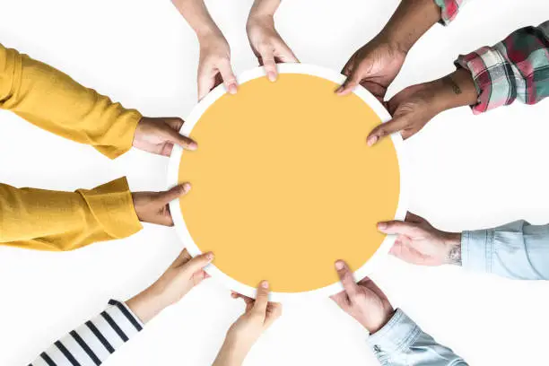 Photo of Diverse hands supporting a blank yellow round board