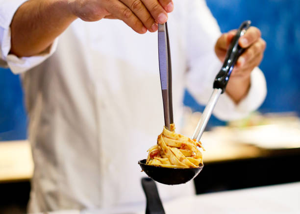 istock Chef cooking pasta, Chef serves spaghetti carbonara on the plate in the kitchen 1125547752