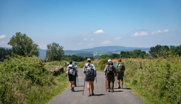 Pilgrims walking the Camino de Santiago A group of pilgrims walk down a country road that is part of the Camino de Santiago near Portomarin, Spain (July 7, 2018) pilgrimage stock pictures, royalty-free photos & images