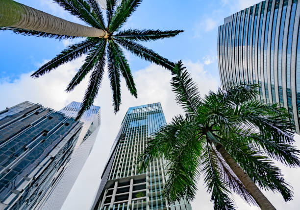 Close-up shot of a low-angle view of a contemporary architectural building in Singapore, featuring geometric glass and steel structures with clouds floating above in the sky.\n\nConcept :\nSingapore architecture, modern building, futuristic skyscraper, abstract structure, low angle cityscape, urban skyline, architectural design, glass facade, steel structure, cloud background, city infrastructure, contemporary construction, Asian metropolis, modern urban design, high-rise building photography, architectural geometry, building exterior, innovative design, city perspective, minimal architecture