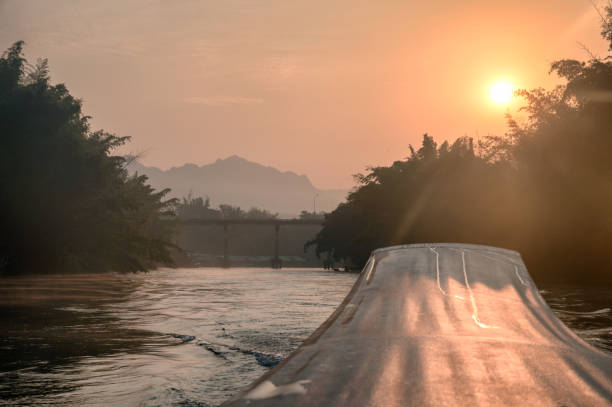 sailing long-tail boat with sunrise on bridge in river kwai - stream forest river waterfall imagens e fotografias de stock