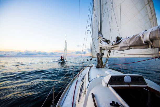 cielo de la tarde claro al atardecer. dos barcos de vela. vista desde la cubierta de proa y velas, primer planos. mar báltico, letonia - watersports centre fotografías e imágenes de stock