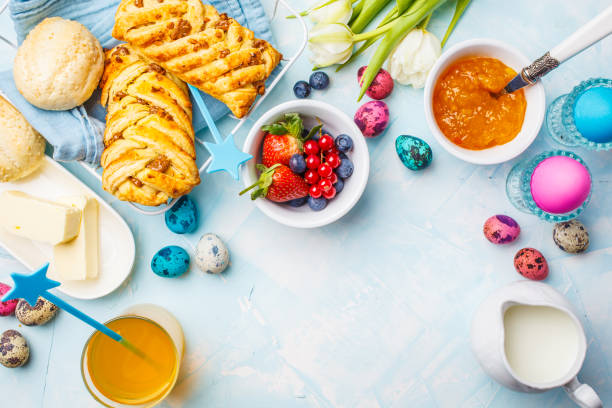 istock Easter Breakfast table. Colored eggs, buns, juice and jam. Blue background, top view, food frame. 1125564655
