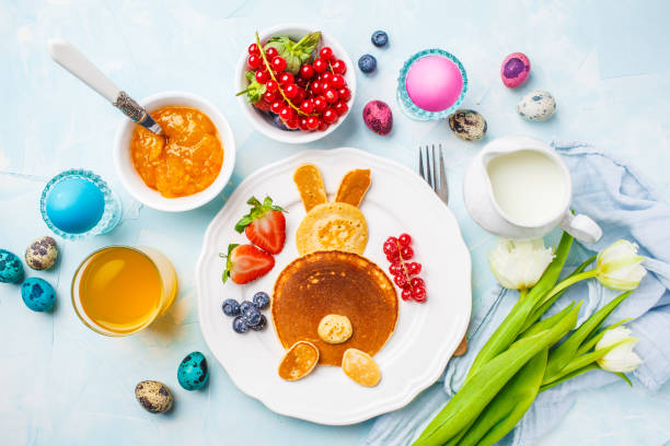 Easter bunny of pancakes with berries. Easter Breakfast table. Blue background, top view. Easter bunny of pancakes with berries. Easter Breakfast table. Colored eggs, milk, juice and jam. Blue background, top view. bunny pancake stock pictures, royalty-free photos & images