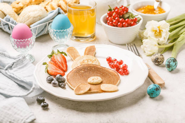 istock Easter bunny of pancakes with berries. Easter Breakfast table. Colored eggs, milk, juice and jam. 1125564817