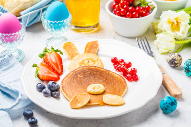 Easter bunny of pancakes with berries. Easter Breakfast table. Colored eggs, milk, juice and jam. Easter bunny of pancakes with berries. Easter Breakfast table. Colored eggs, milk, juice and jam, white background. bunny pancake stock pictures, royalty-free photos & images