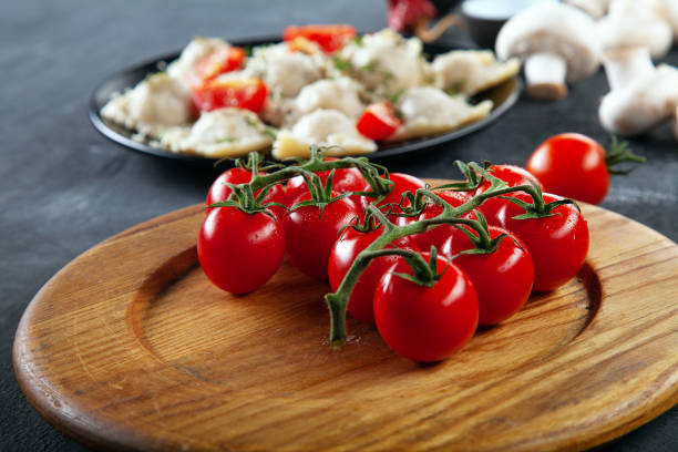 istock Close up view on fresh cherry tomatoes  for use as cooking ingredients for ravioli. Tomato on wooden desk in front of mushrooms and ravioli. Free copy space for text. 1125568783