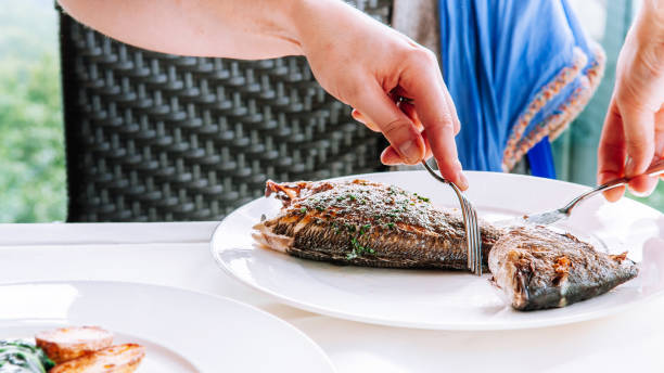 istock Woman carving grilled fish from its bones 1125571222