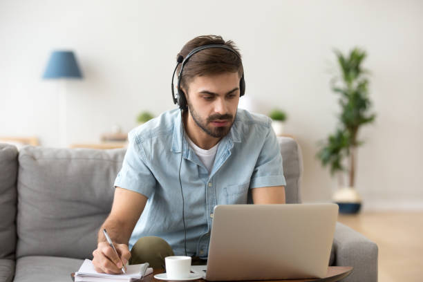 istock Serious man looking at laptop wearing headset learning foreign language 1125572469