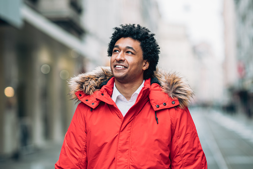Young african american man with red jacket walking on the street