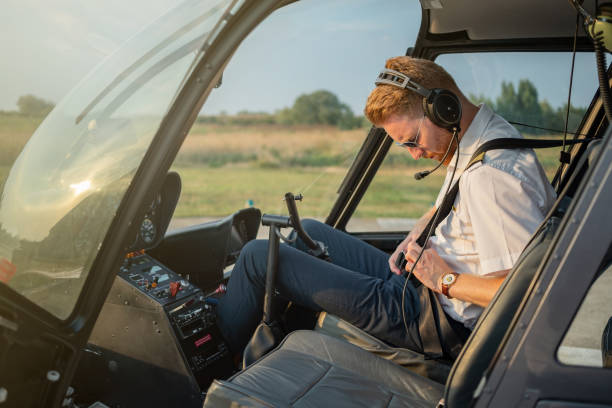 helicopter pilot fastening seat belt in cockpit - aviator glasses audio imagens e fotografias de stock