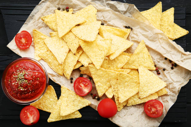 istock Potato chips with sauce and tomatoes on black wooden table 1125582932