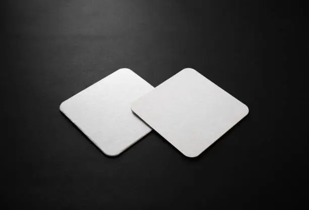 Blank square beer coasters mockup on black background.