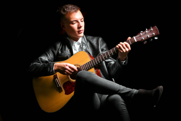istock Young men playing the guitar with black background 1125586914