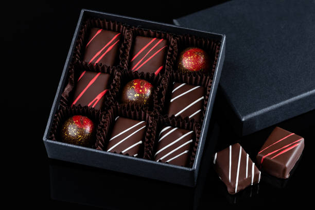 assortment of luxury bonbons with red splashes in box on black background - craft chocolate candy black box imagens e fotografias de stock