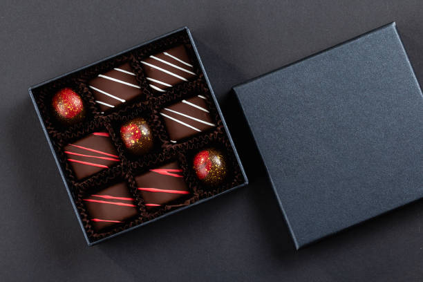 Assortment of luxury bonbons with red splashes in box on black background stock photo