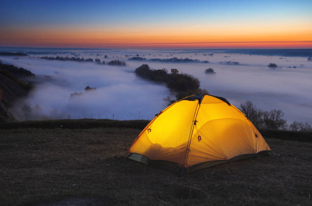 istock Illuminated from inside orange tourist tent over misty river 1125588704