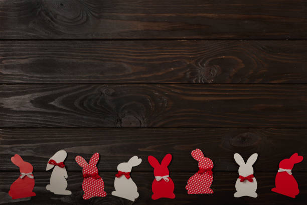 Happy Easter! Easter decoration - Easter bunnies with ribbons - red, white and red with white polka-dot flowers on a brown wooden background. Selective focus.