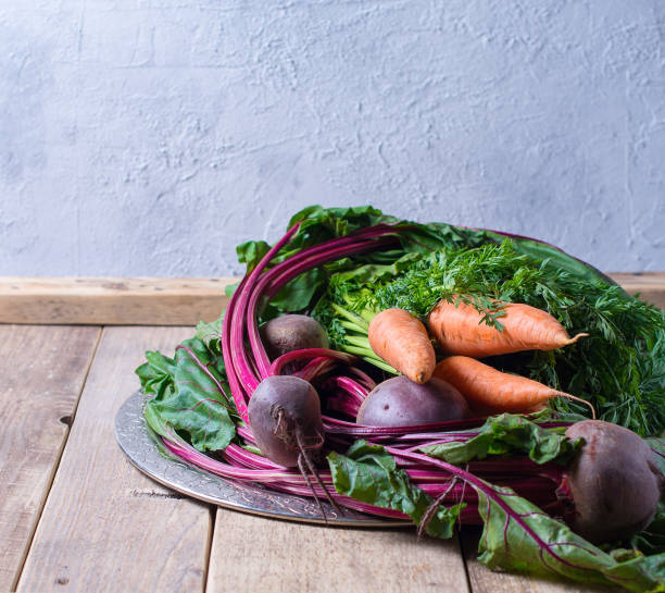 Group of beetroot and carrots on plate on wooden background, rustic