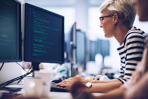 Ver perfil de joven mujer programador trabajando en software de computadora en la oficina. photo
