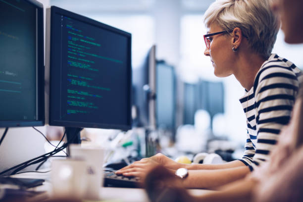 profiel van jonge vrouwelijke programmeur bezig met computersoftware in het kantoor te bekijken. - code stockfoto's en -beelden