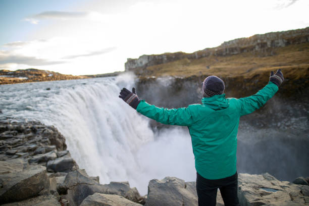 istock Happy tourist against Dettifoss waterfall background 1125597392