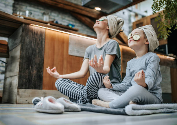 sotto la vista di madre e figlia meditare durante il trattamento di bellezza a casa. - spirituality yoga zen like meditating foto e immagini stock