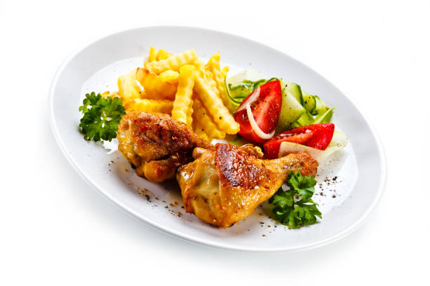 istock Roasted chicken drumsticks, French fries and vegetables on white background 1125601821