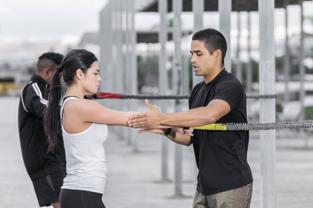Instructor teaching woman to exercise with band