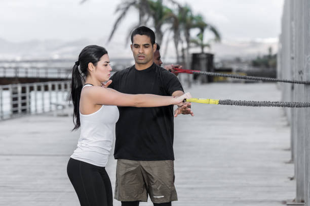 istock Trainer helping woman with resistance band exercise 1125602577