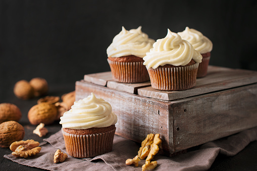 Carrot cupcakes or muffins with nuts on dark background, copy space