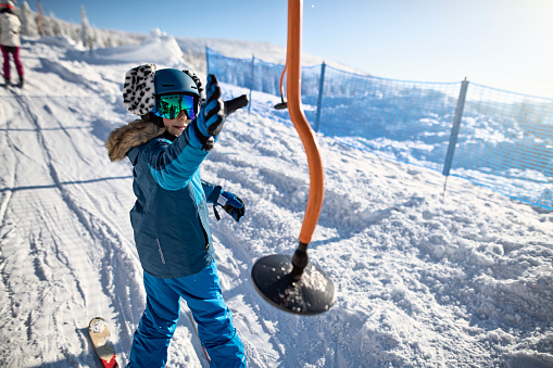 Little boy skiing on a beautiful sunny winter day. Little boy catching a platter hanger on a platter ski lift.
Nikon D850