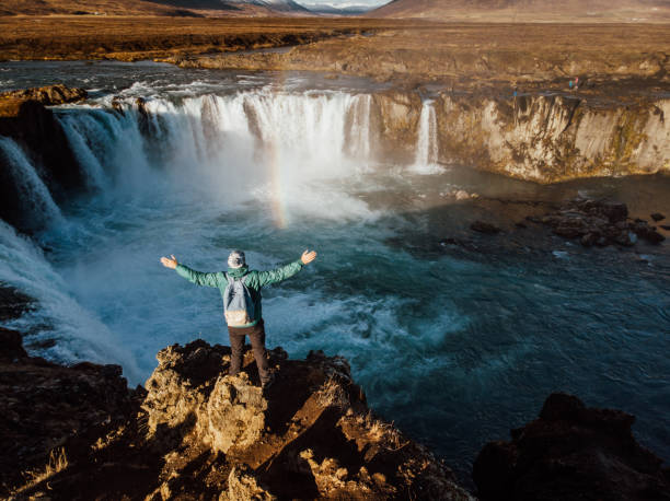 istock Man looking at scenic view of waterfall in Iceland 1125607207