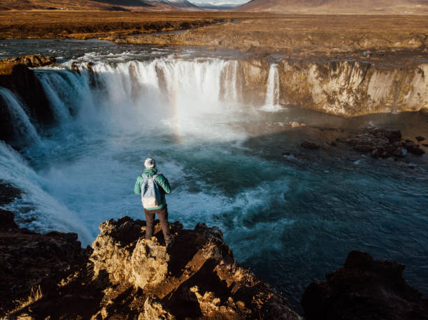 istock Man looking at scenic view of waterfall in Iceland 1125607281