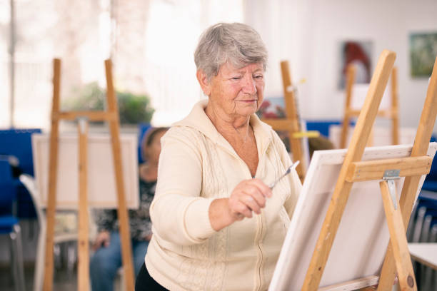 istock An elderly woman self-fulfilling, painting on canvas. 1125611321