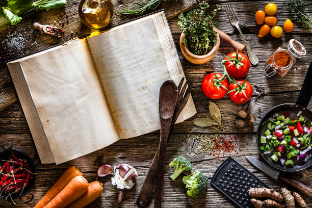 książka kucharska z warzywami, przyprawami i ziołami nakręcona z góry na rustykalnym drewnianym stole - książki kucharskie zdjęcia i obrazy z banku zdjęć