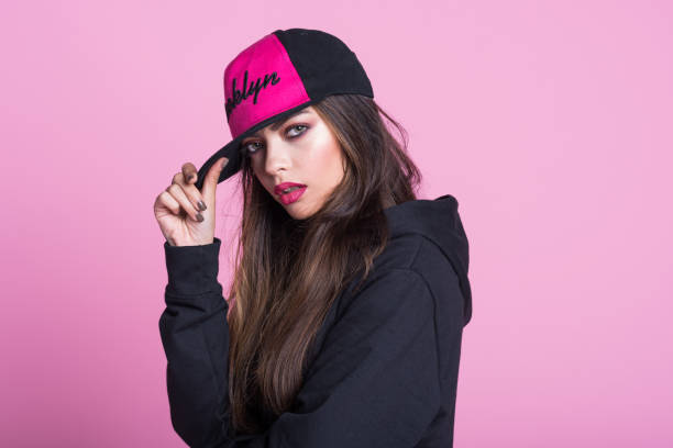 mujer joven en camisa con capucha negra sobre fondo rosa - gangsta rap fotografías e imágenes de stock