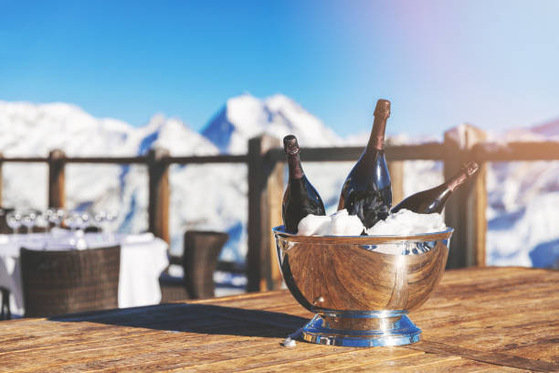seau avec des bouteilles de champagne sur la table de restaurant sur fond de montagne enneigée - winter palace photos et images de collection