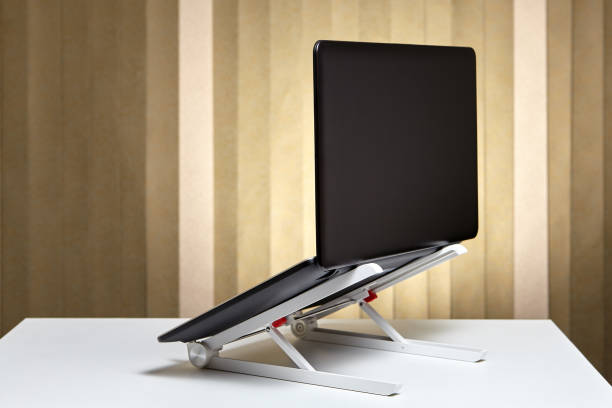 The laptop is open and mounted on a cooling stand. Adjustable portable aluminum laptop  holder folding with open pc notebook, back view. adjustable stock pictures, royalty-free photos & images