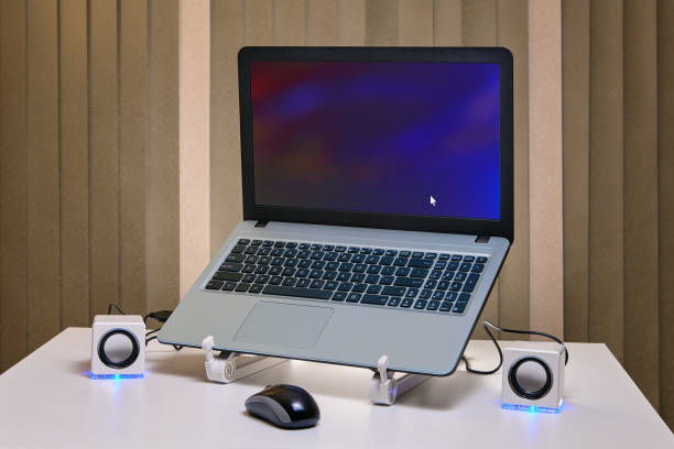 istock Computer mouse and miniature speakers next to the started laptop. 1125614893