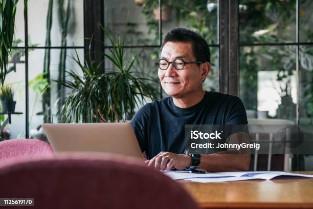 Sonriente Hombre Chino Trabajando En Ordenador Portátil En Casa Foto de stock y más banco de imágenes de Hombres