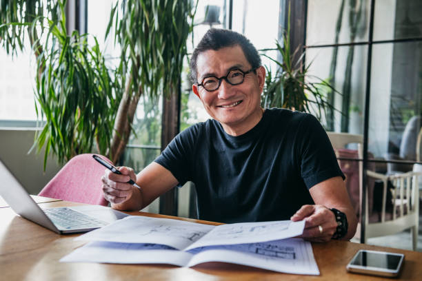 istock Cheerful Chinese man working from home with paper document 1125619175