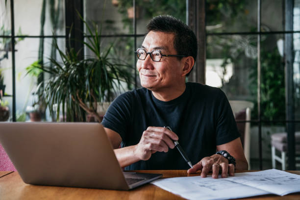 maduro hombre chino utilizando el portátil en casa - working at home mature adult small business laptop fotografías e imágenes de stock