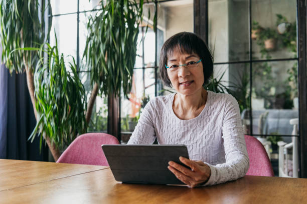 istock Senior Chinese woman using tablet and looking at camera 1125619344